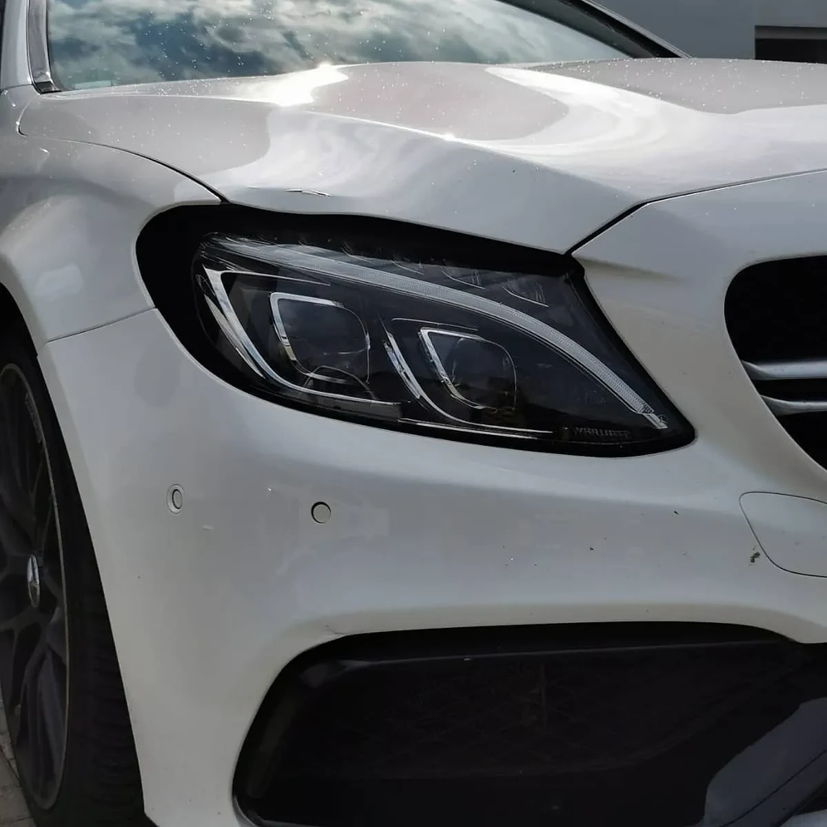 Detail der lackierten Fahrzeugfront eines weißen Mercedes